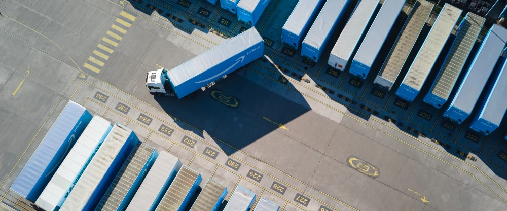 Aerial view of a logistics facility with blue and white loading docks and a truck maneuvering in the parking area.
