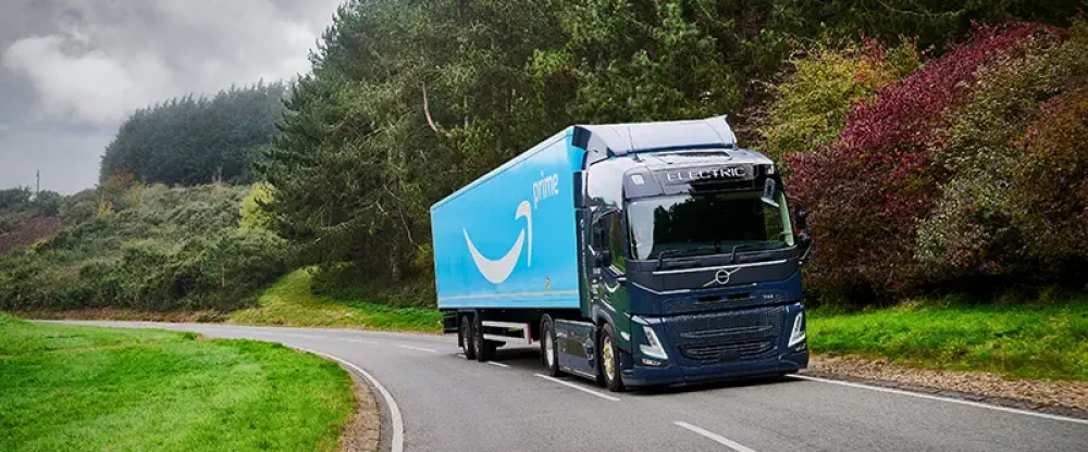 A Prime shipping truck traveling down a road surrounded by greenery and trees
