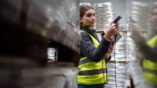 A woman in a safety vest takes a measurement